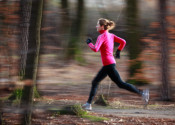 Young woman running outdoors in a city park on a cold fall/winte